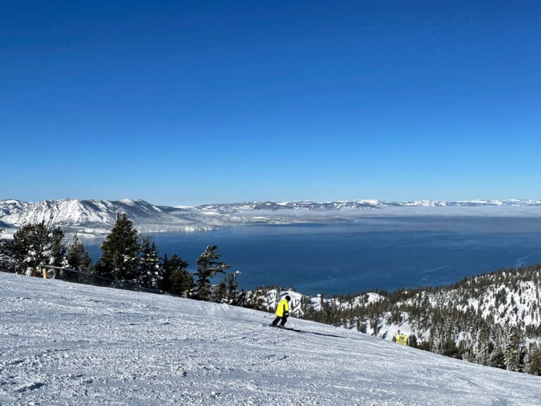 Scenic view of skiers and snowboarders on the slopes of a ski resort on a bluebird winter day, with Lake Tahoe in the background Northstar Ski Rental Delivery