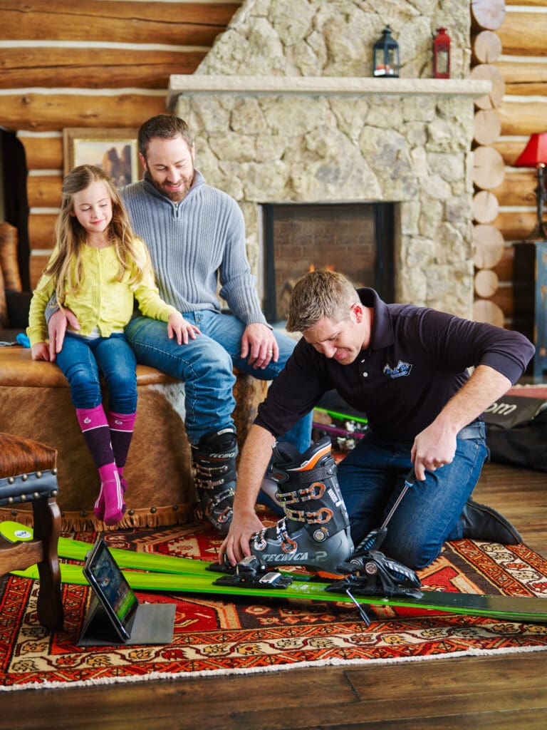 Black Tie Ski Rental Delivery expert technician checking boot and ski fitting with family at the lodge