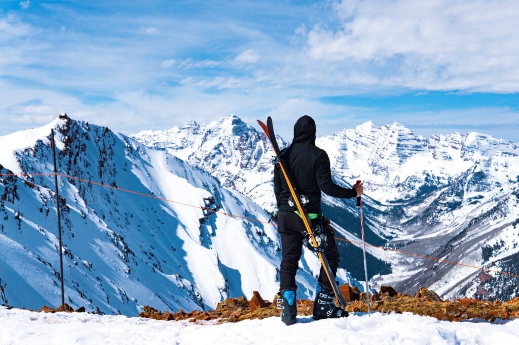 Man With Skis And Ski Pole At Summit Of Massive Winter Mountain Landscape