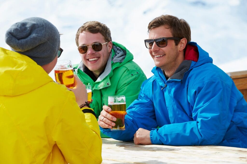 Group Of Young Men Enjoying Drink In Bar At Ski Resort